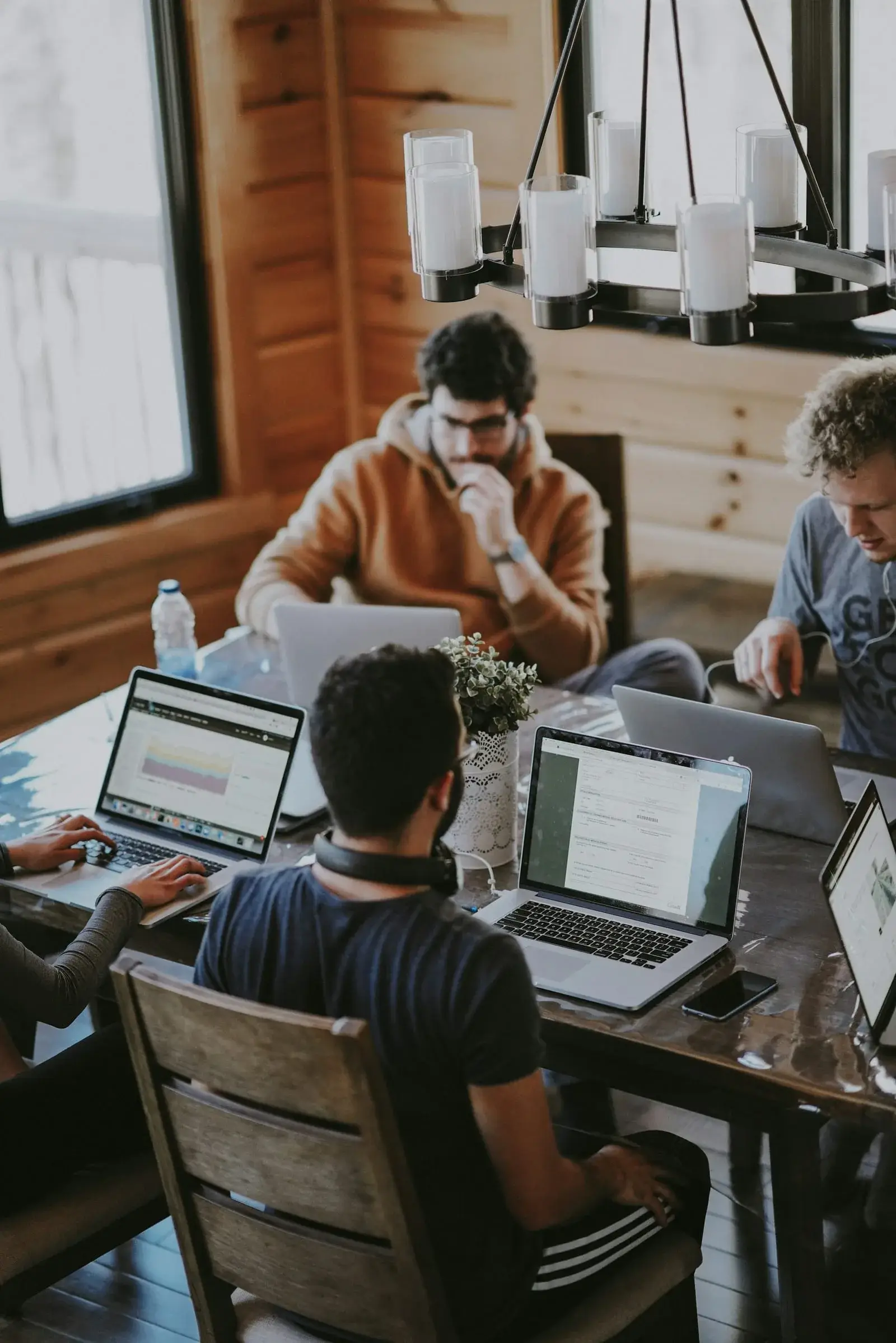 A small team working together on laptops around a wooden table